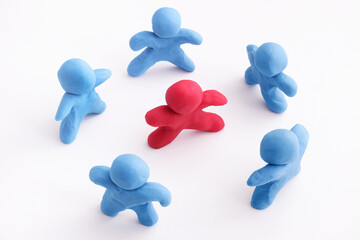Blue plasticine people surrounding red plasticine person. Stand out from the crowd. Bullying...