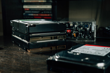 Obraz premium The stack of HDDs on the office table with case for storage data disks at the background