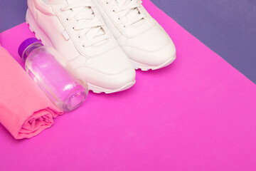 Fototapeta na wymiar Fitness concept with white sneakers, water bottle and towel. on a pink background. Copy space