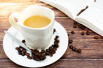 Cup of coffee with book in background on wooden texture