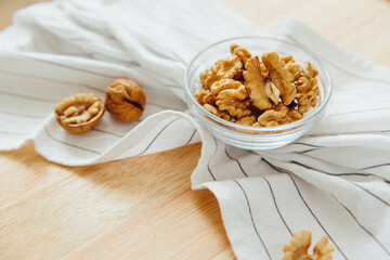 Still life: peeled walnuts in bowl lie on kitchen table.