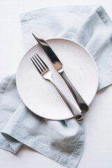 An empty plate and Cutlery on a white table. Top view.