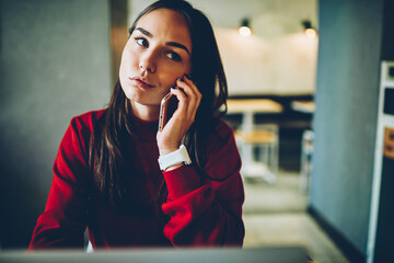 Emotional hipster girl surprised with winning online contest talking with operator on mobile phone