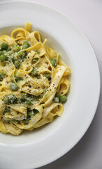 Tagliatelli con Limone e Piselli on white plate corner view