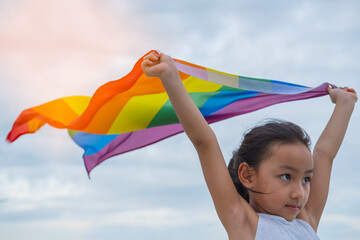 Rainbow flag symbol of love or LGBT pride concept.,Young girl show rainbow flag overhead. June pride month to celebrate pride festival, liberty right, freedom, proud to be equal and legal marriage.