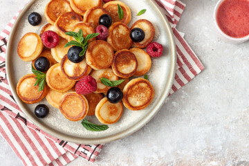 Bowl with mini pancake cereal with raspberries, mint and blueberries.Trendy food