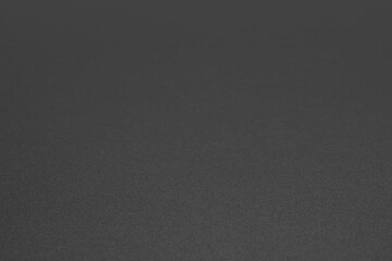 Black grained chalkboard surface with shallow depth of field and copy space. Abstract trendy textured background with selective focus.