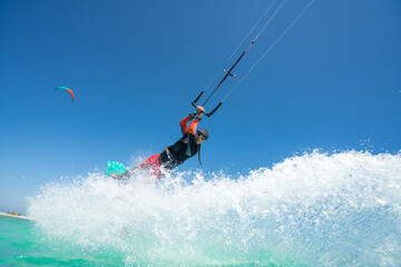 kiter does a difficult trick on a background of transparent water and blue sky