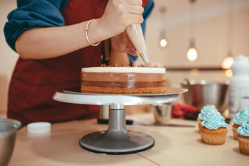 Fototapeta na wymiar Pie hand decorating a three-color cake.
