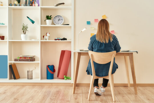 Creative workplace. Young woman in casual clothes sitting at office desk, working or studying at home office. Working remotely