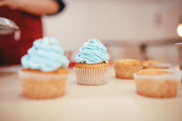 Three cupcakes with blue icing. Wooden bottom, a pastry shop