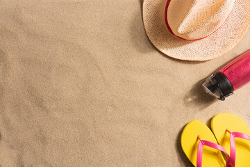 Fototapeta na wymiar Summer vacation composition. Water bottle, flip flops and straw hat on sand