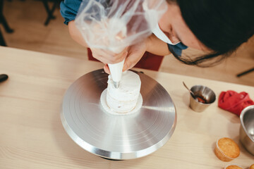 Detail of an Asian pastry maker smoothing glaze on a mini cheese cake with strawberries.