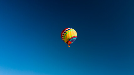 Fototapeta na wymiar A lone balloon rises high in the blue sky