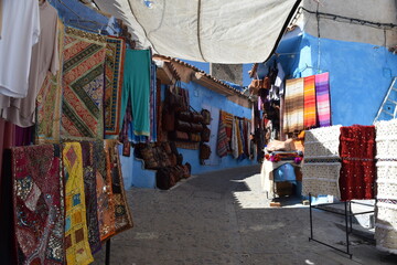 Small shops selling colorful carpets on the narrow streets of Chefchaouen, the blue city in Morocco