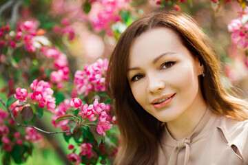 Fototapeta premium portrait of a beautiful young woman with make-up near a tree with flowers