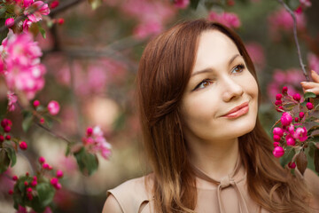 Naklejka premium portrait of a beautiful young woman with make-up near a tree with flowers