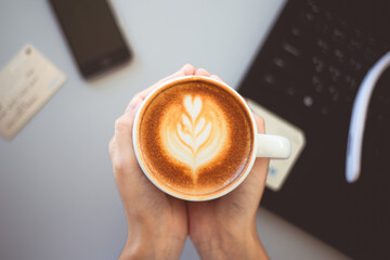 Hot coffee on hand in a coffee shop There are props, notebooks, credit cards, headphones and phones.