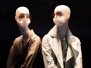 Mannequin girls in medical masks. Window reflection of modern fashion clothing store. Closed until further notice. Closed modern clothing store