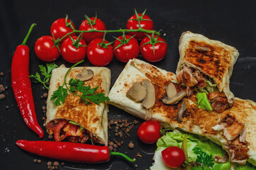 Shawarma cut in half with chicken meat on a black background. View from above. Cheese, red pepper parsley. Street Food, Fast Food, Oriental Food