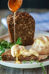 Delicious treat white soft round cheese with mold with honey and craft bread. Selective focus