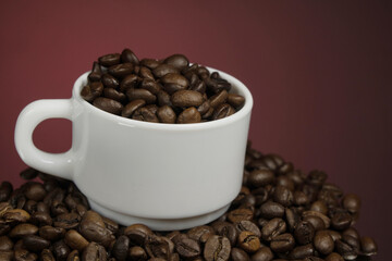 White mug with coffee grains sprinkled with coffee grains on a background
