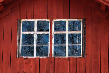 Old house facade with broken window panes from a typical red Swedish house