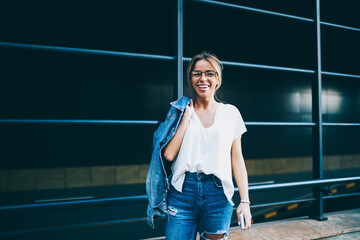 Young woman in optical eyeglasses walking in urban setting