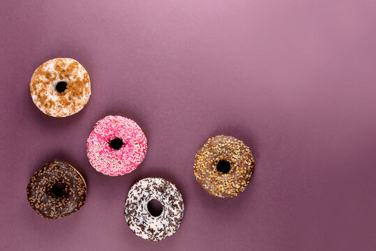 Different donuts on a brown background top view stock images. Different donuts isolated on a brown background with copy space for text. Doughnut frame stock images