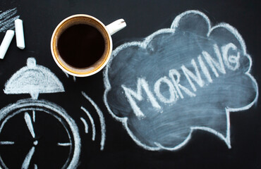 
The alarm clock is drawn in white chalk on a blackboard, a mug of hot coffee and the inscription:...