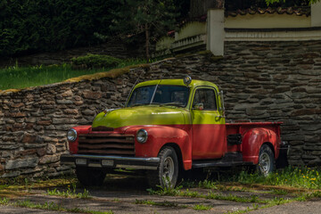 Old classic veteran car with silver red yellow colors and stone wall