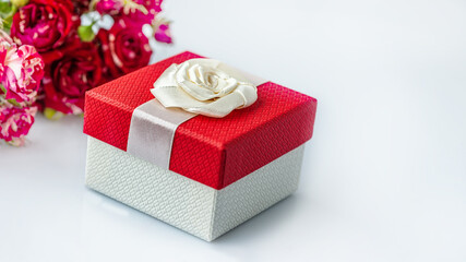 Red gift box and a bouquet of roses on a white background with a copy of the space