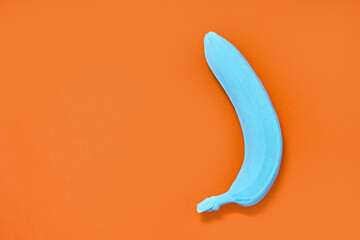 painted blue banana on an orange background. copys pace. concept design
