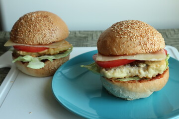 Homemade fishburgers with slices of tomato, cheese, leafy greens and mustard