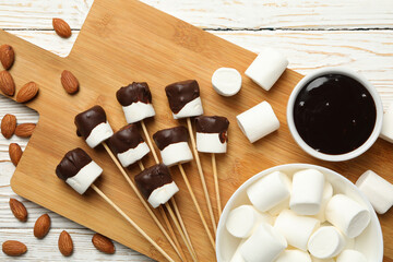 Almond and marshmallow in chocolate on white wooden background, top view