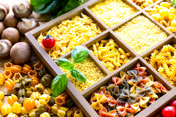 Different types of italian uncooked pasta in wooden box, whole wheat pasta, pasta, spaghetti, noodles, tagliatelle. Top view.