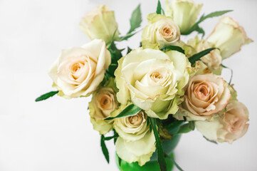 Romantic bouquet of delicate greenish roses on a light background. Background of cream and pink roses. Close-up, selective focus