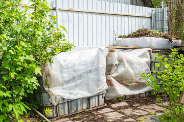 Plastic containers are reused for composting waste in the garden. fresh composted earth from the...