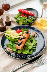 Close-up of grilled salmon fillet with green bean sprouts with avocado on a plate. Dietary food in case of involuntary quarantine