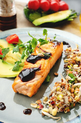 Close-up of grilled salmon fillet with green bean sprouts with avocado on a plate. Dietary food in case of involuntary quarantine