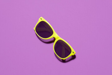 Yellow sunglasses top view / flat lay on a purple background with a centre composition