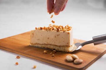 Hand of woman decorating with chopped almond on portion of semifred cake of nougat mouse