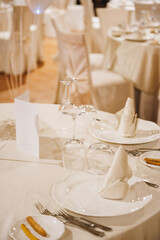 Decorated banquet table at wedding, on table plates, menu, forks, wine glasses, napkins, bread