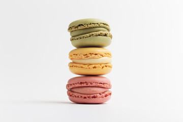 Pink, green and yellow macarons on white background