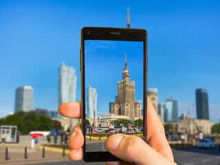 A hand is taking photo of Warsaw skyline with modern smartphone