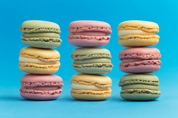 Pink, green and yellow macarons on blue background