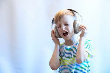 Funny boy in headphones listens to music and sings a song