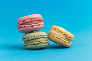 Pink, green and yellow macarons on blue background