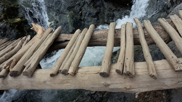 Broken bridge made of branches and thin trunks in front of a waterfall, Setti Fatma, Morocco