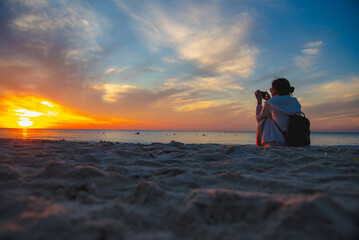 The girl sat using a mobile phone to take pictures of the sun that the man had lost.